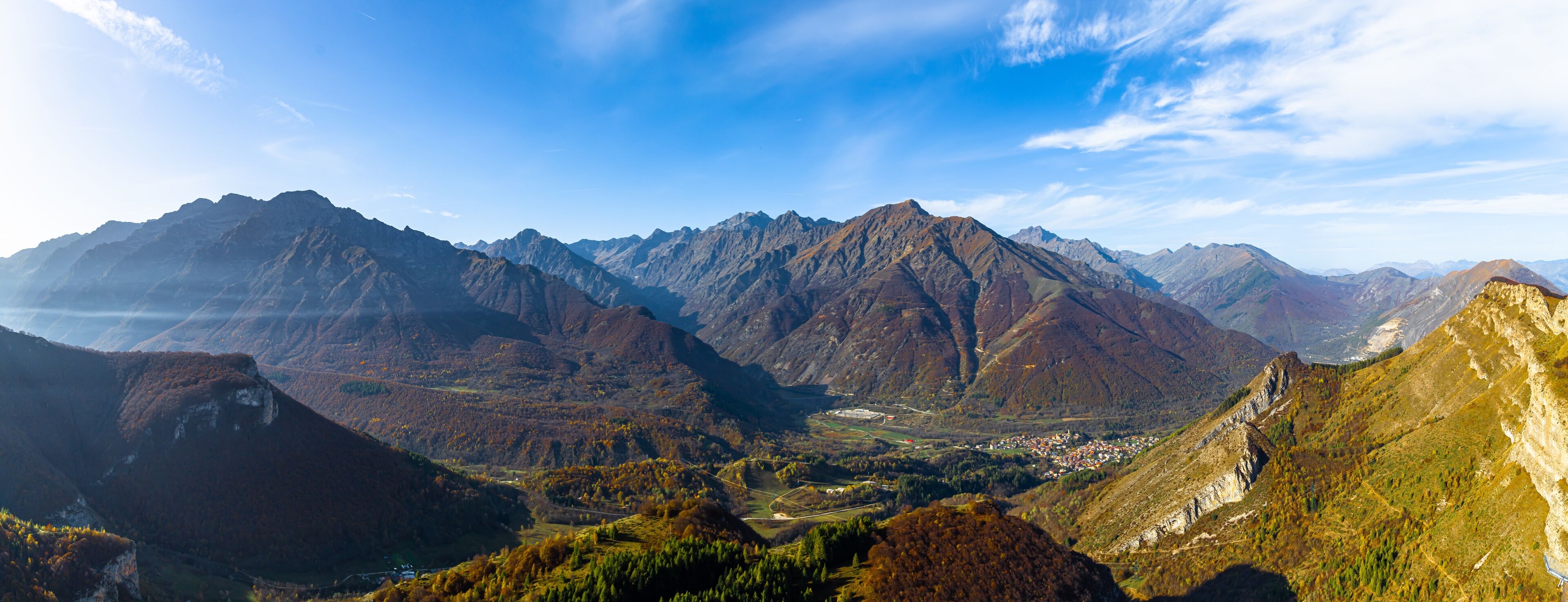 A mountainous landscape with a valley, a small town, and a river.