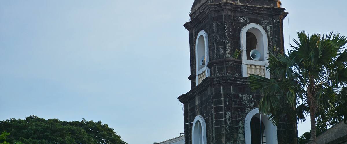 A church tower with a cross on top, arched windows, and a dome.