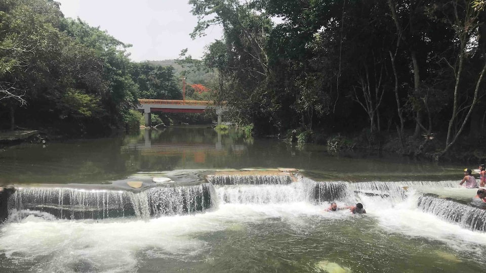 A waterfall with people swimming in the water.