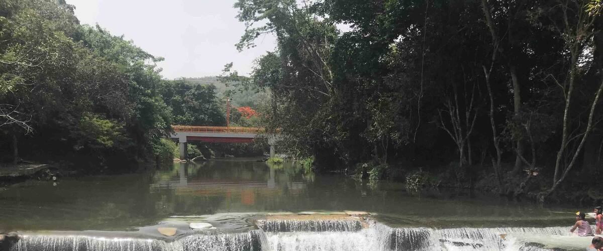 A waterfall with people swimming in the water.
