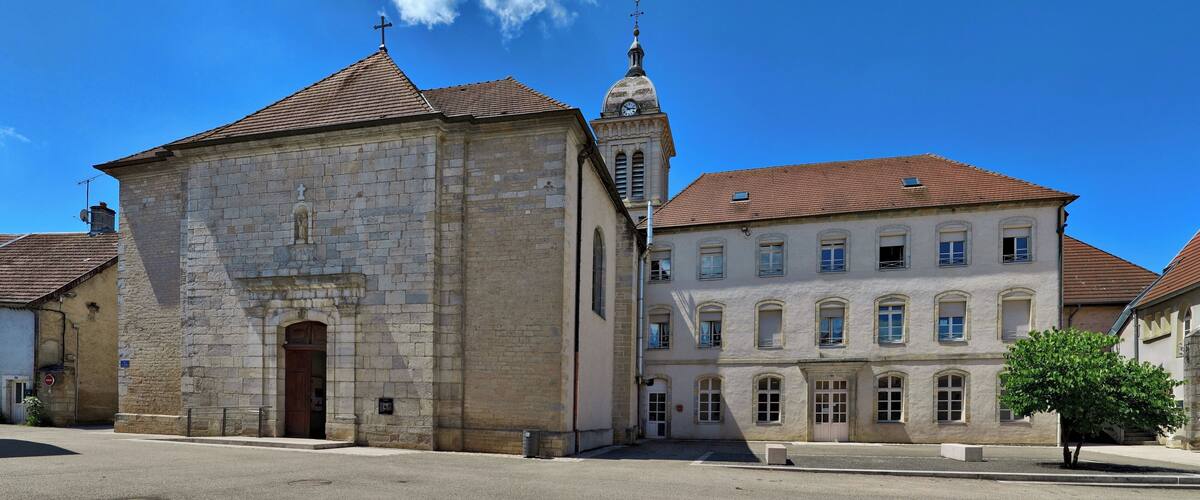 A historic stone church with a clock tower and a large building with arched windows.