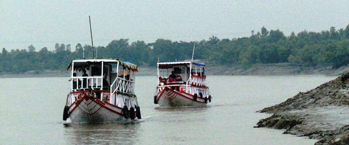 Two boats on a calm river with a forested shoreline.