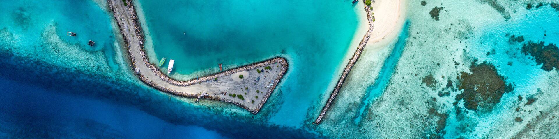 Aerial view of local, inhabited island Felidhoo, located in Vaavu Atoll, Maldives, Indian Ocean with boats / dhonis anchored in the harbour and local beach