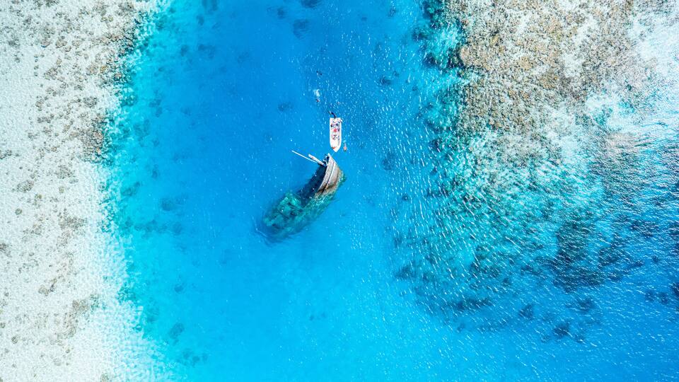 Aerial view of a ship wreck and a boat near Keyodhoo, Vaavu Atoll, Maldives, Indian Ocean with people snorkeling