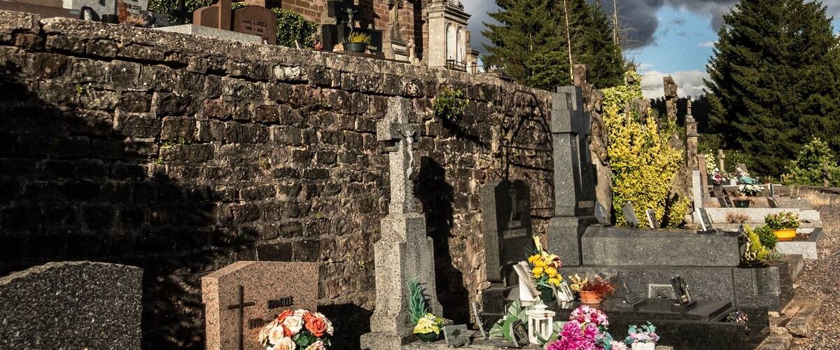 A church with a tall steeple and a cemetery with gravestones and flowers.