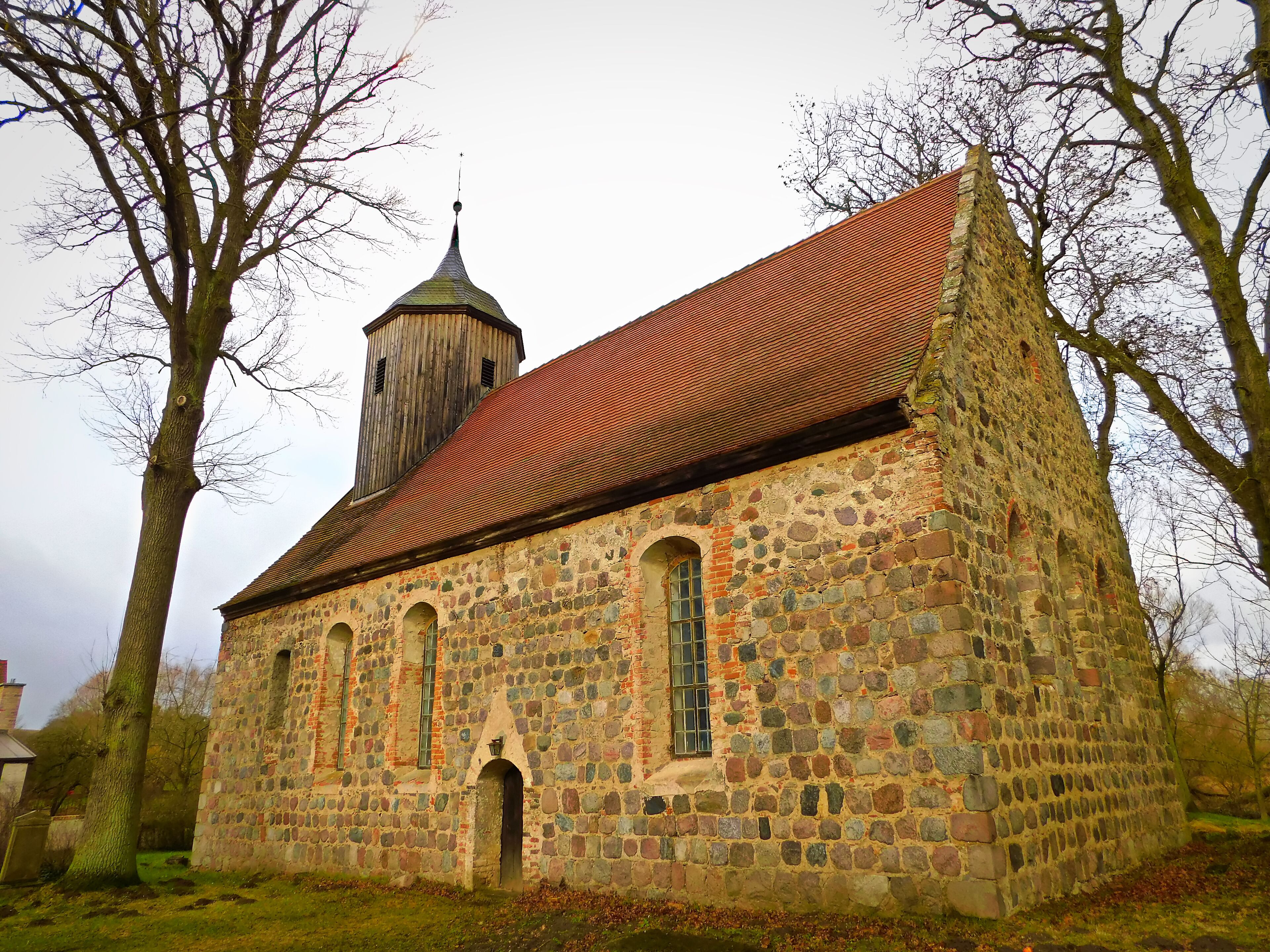 A historic stone church with a red-tiled roof and a bell tower.