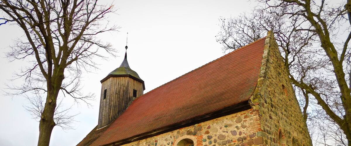 A historic stone church with a red-tiled roof and a bell tower.