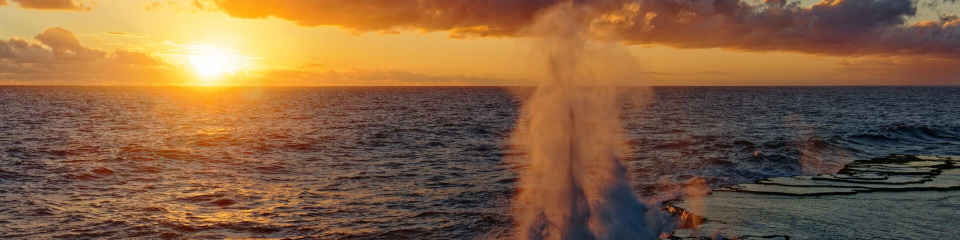 Um pôr do sol sobre o oceano, com o spray da água.