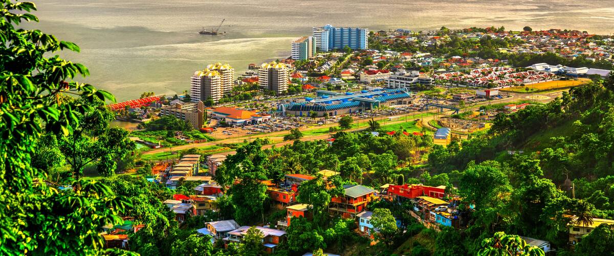 A coastal cityscape with a marina, high-rise buildings, and lush greenery.