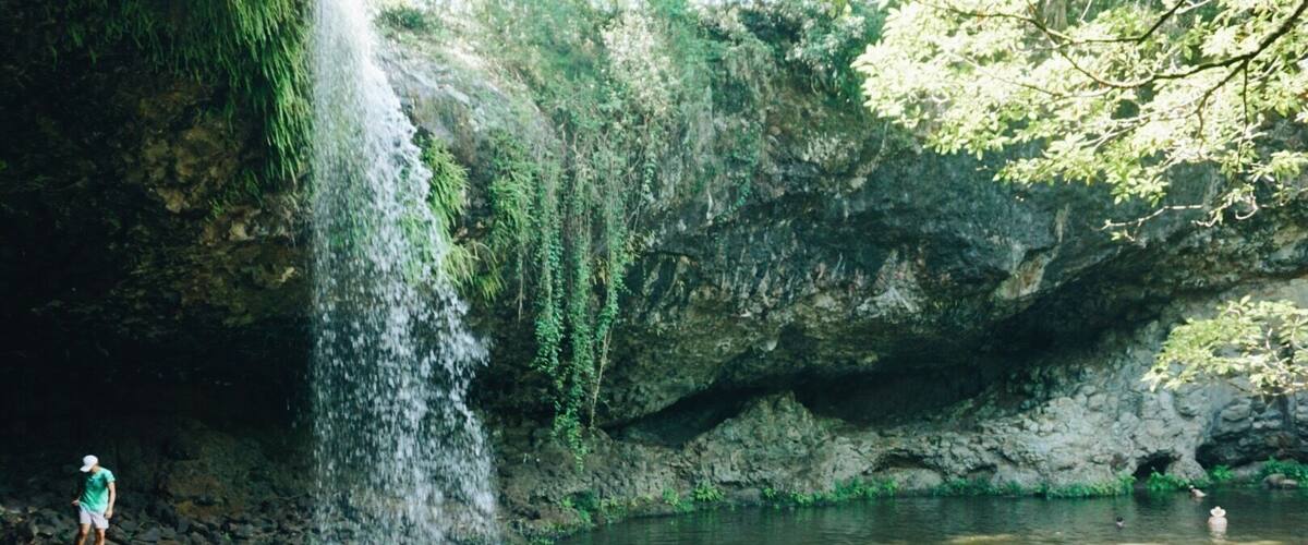 A waterfall in a cave with people enjoying the water.