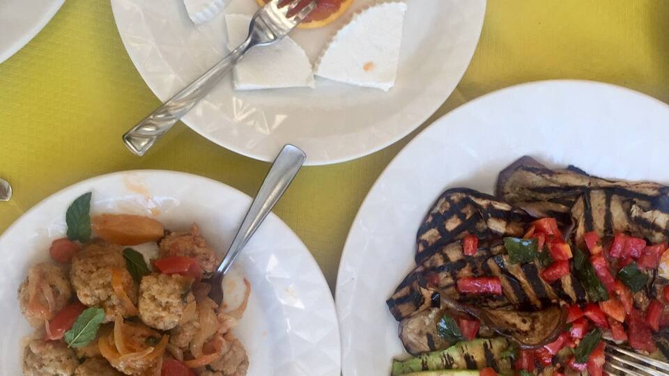 Three plates of food on a yellow tablecloth.