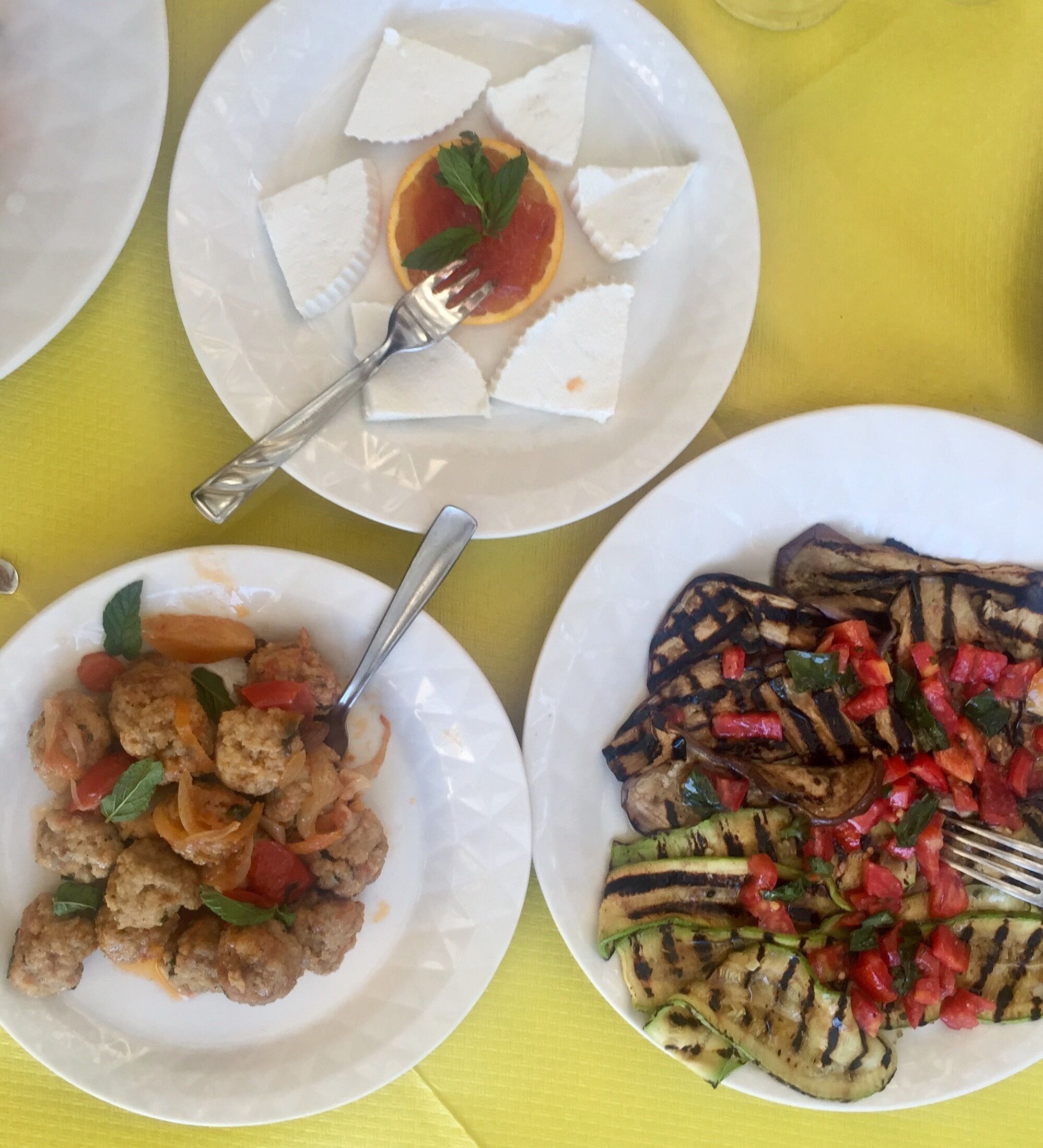Three plates of food on a yellow tablecloth.