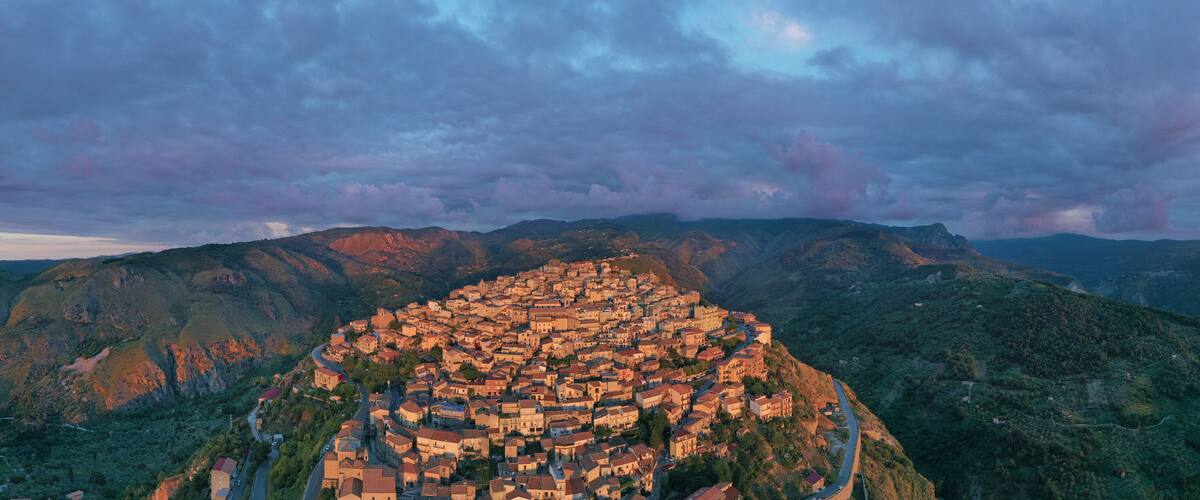 A mountainous town nestled in a valley with winding roads and dense greenery.