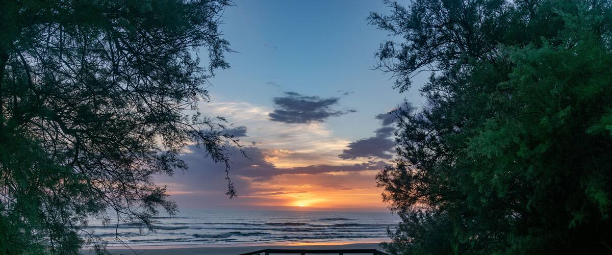 A wooden staircase leading to a beach with a sunset in the background.