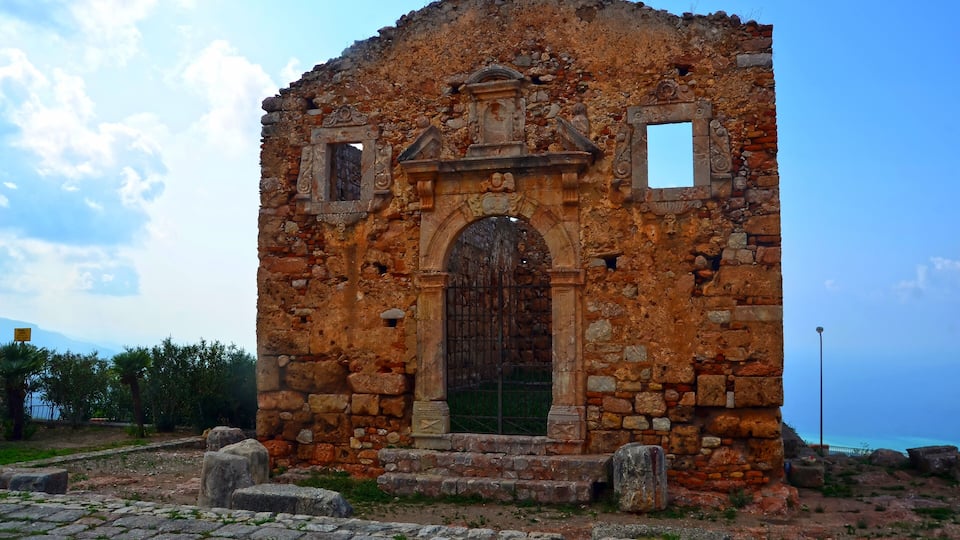 An ancient stone building with a large arched doorway and decorative elements.