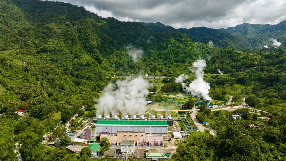 A power plant surrounded by lush green hills.