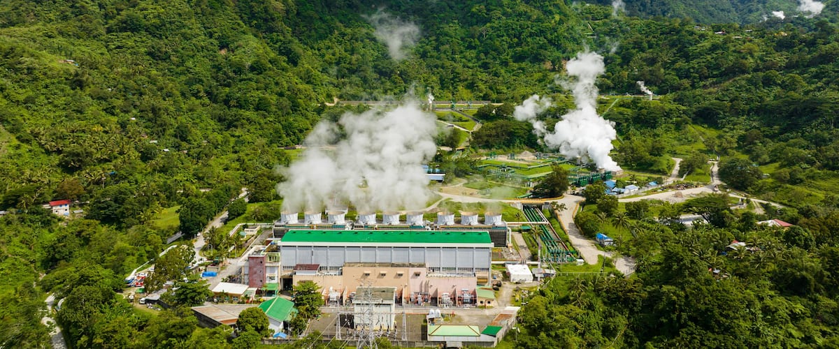 A power plant surrounded by lush green hills.