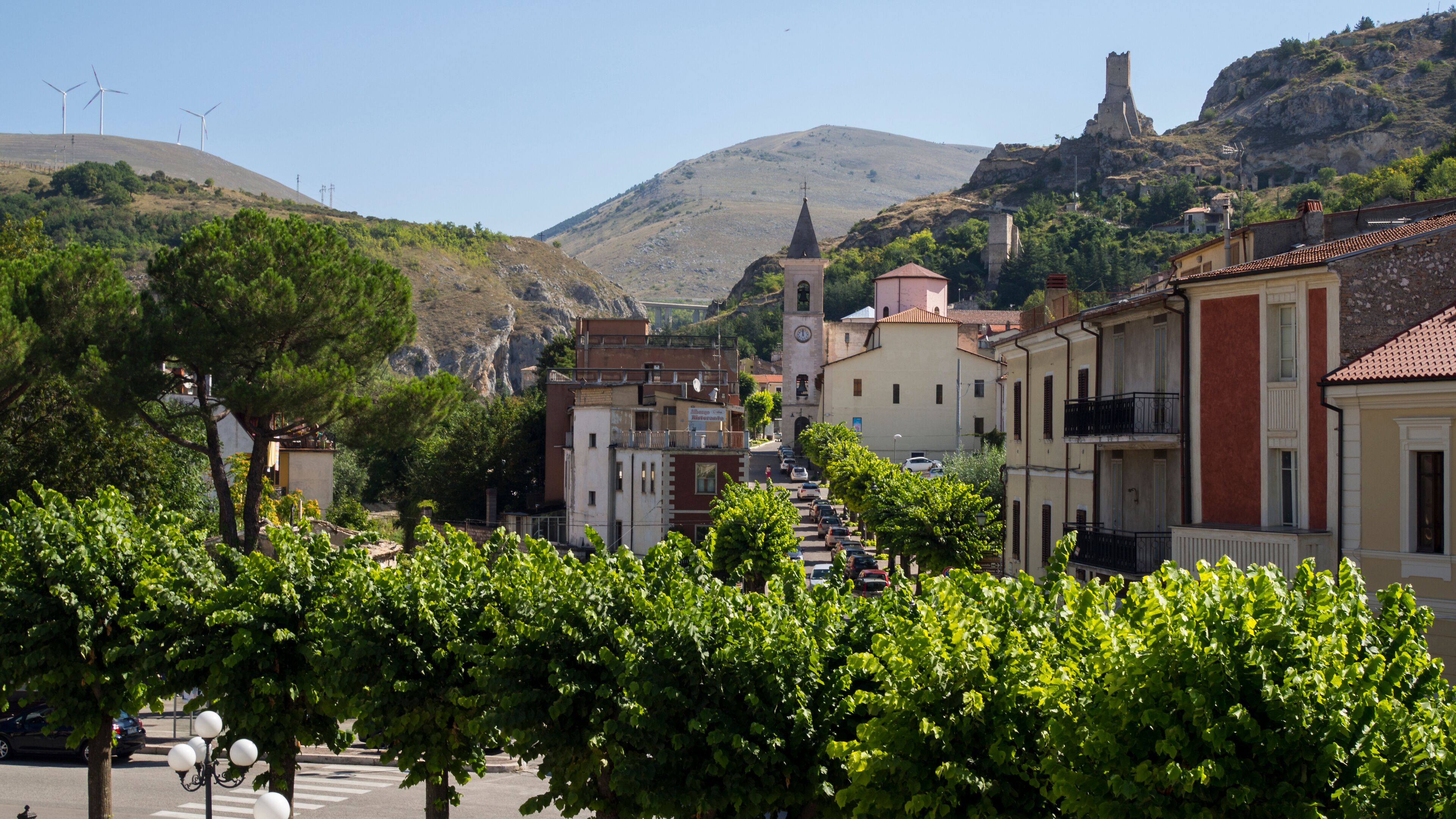 A town with a church, wind turbines, and a castle on a hill.