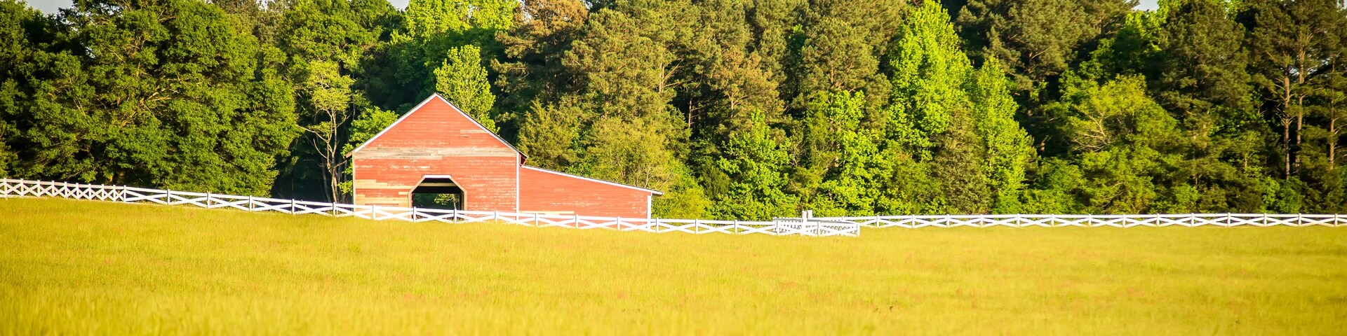 white fence leading up to a big red barn