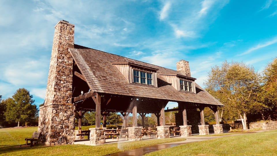 A stone house with a wooden roof and a covered patio area.