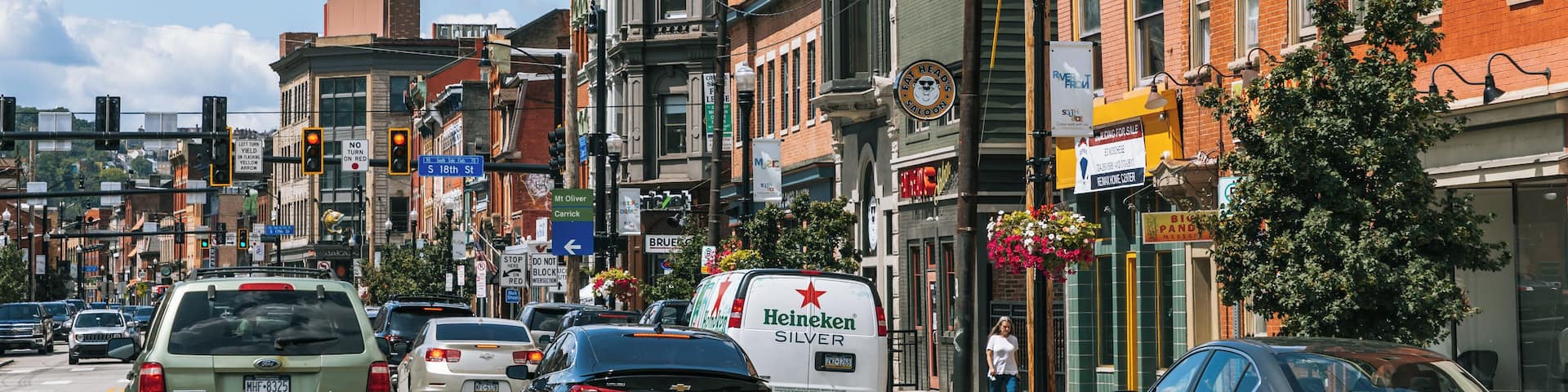 A busy urban street with vintage buildings, cars, and a Heineken van.