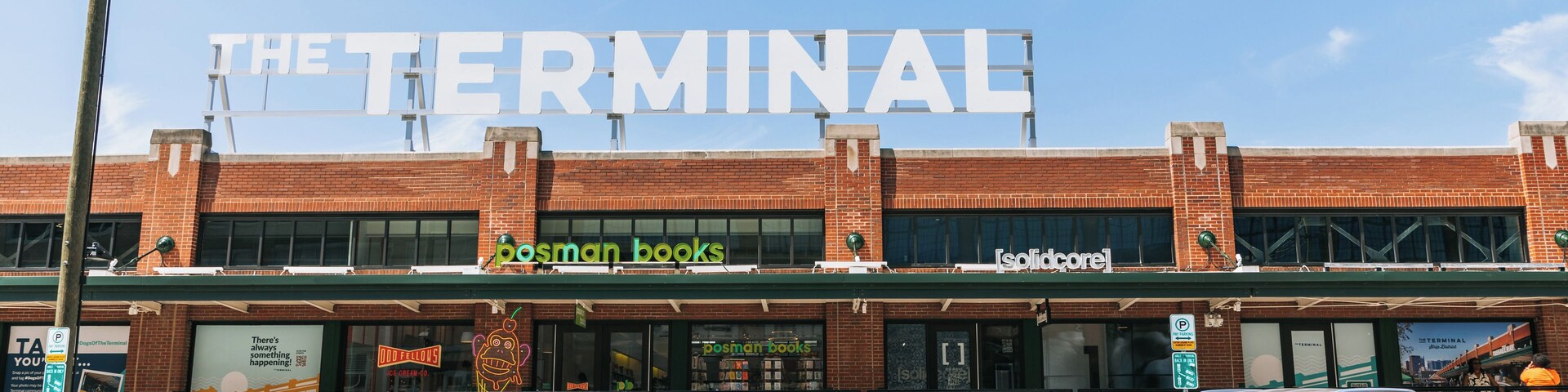 Un edificio con un gran letrero que dice 'THE TERMINAL' y locales de 'posman books' y 'solidcore'.