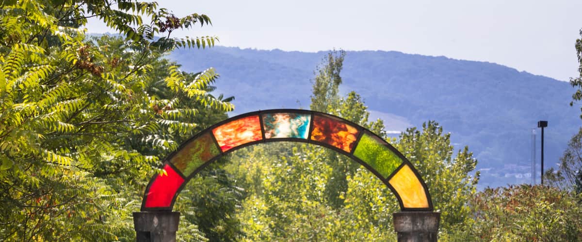 A colorful stained glass archway over a road with a sign reading "Prospect Road Connell's Swell" and "Ride Single File Keep Right".
