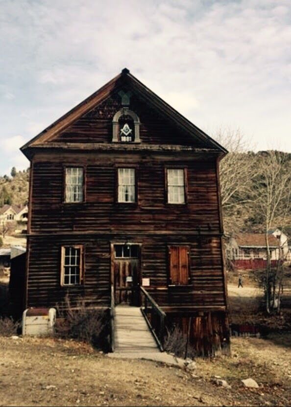 A rustic wooden house with a porch and a small staircase leading to the front door.