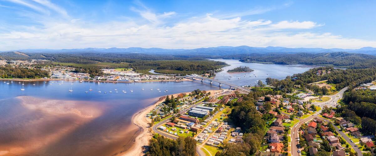 A coastal town with a beach, marina, and surrounding hills.