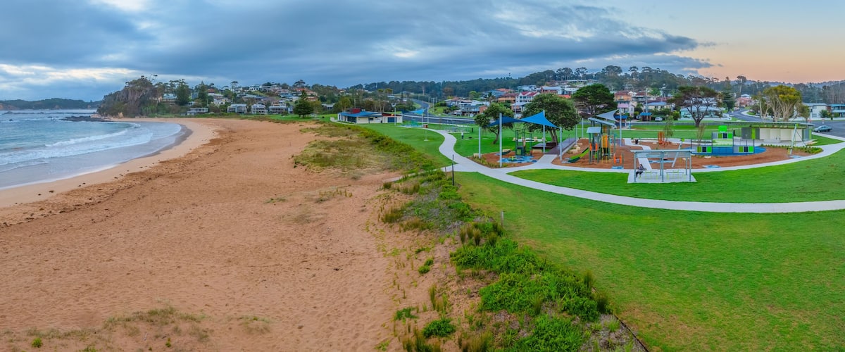 A beach with a playground and houses in the background.