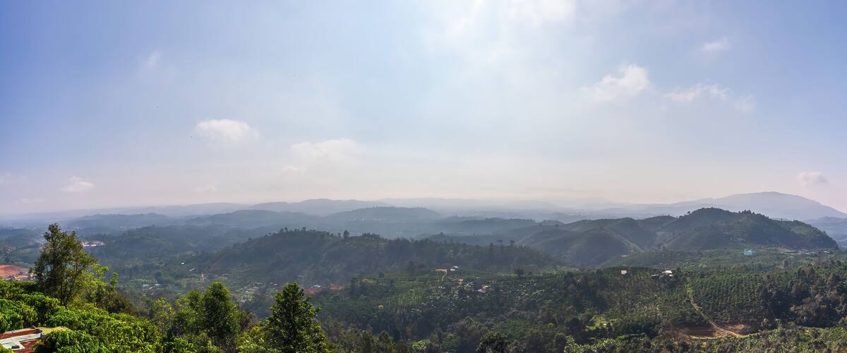 A mountainous landscape with lush greenery and scattered buildings.