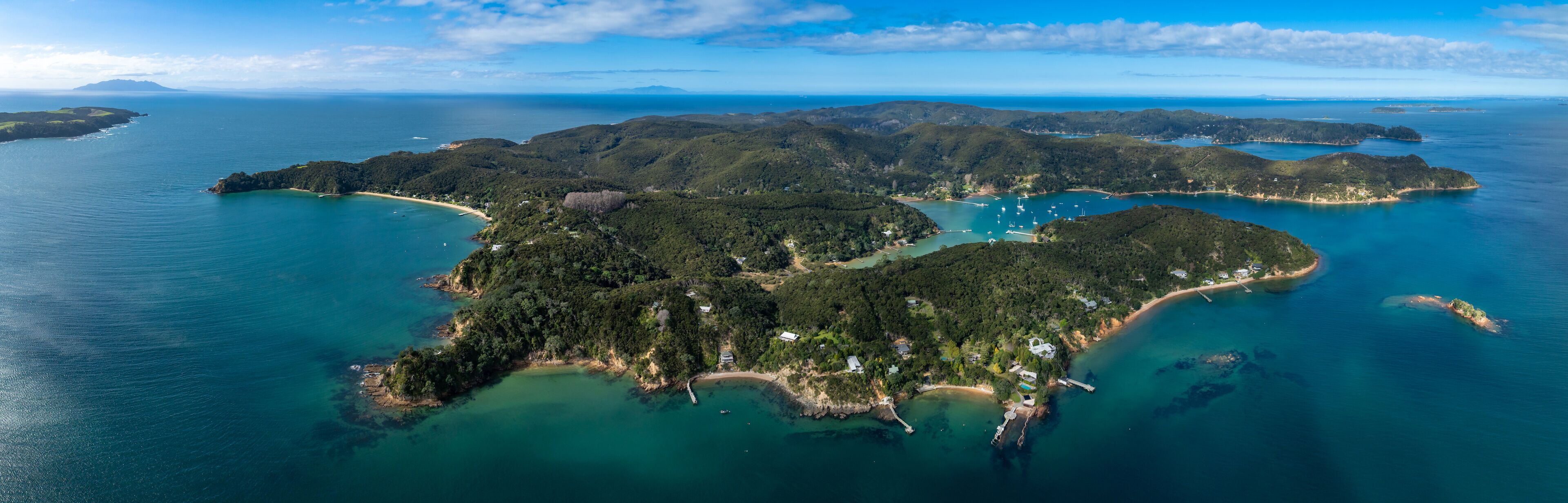 An aerial view of a tropical island with lush greenery, clear turquoise waters, and a small beach area.