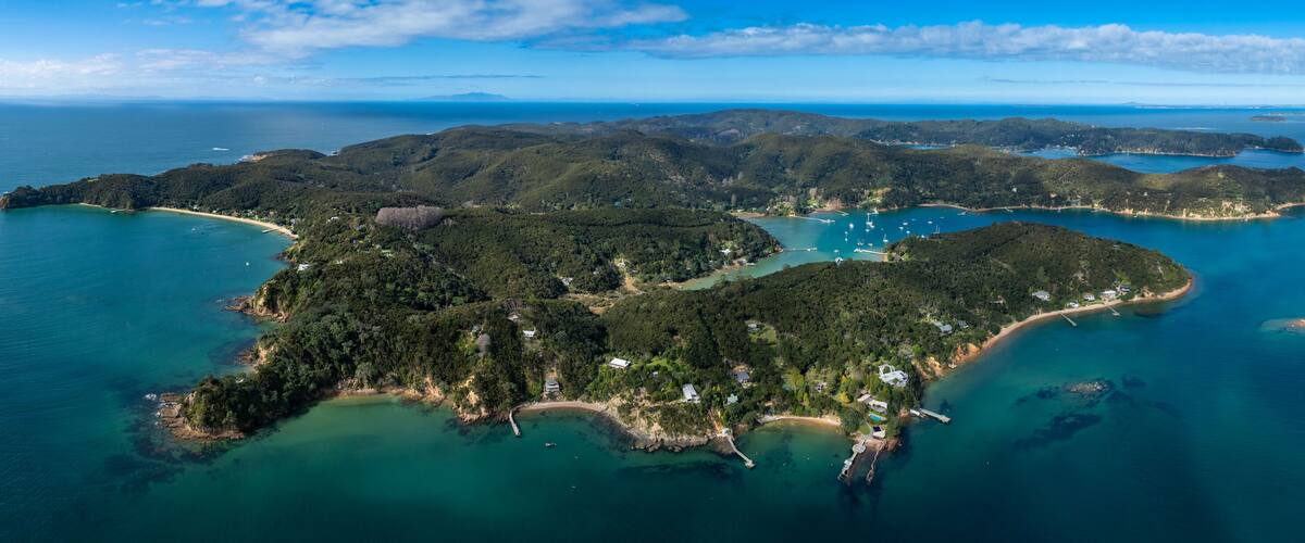 An aerial view of a tropical island with lush greenery, clear turquoise waters, and a small beach area.
