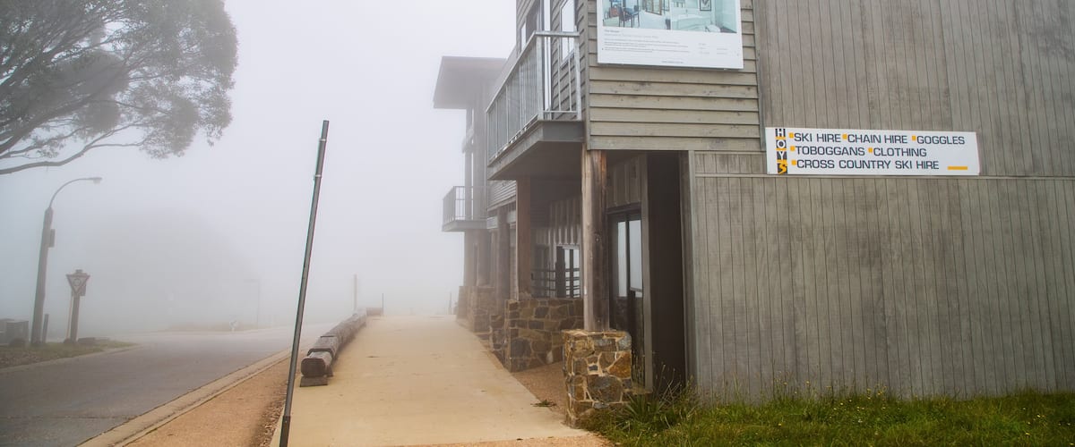 A foggy street with a building displaying a signboard.