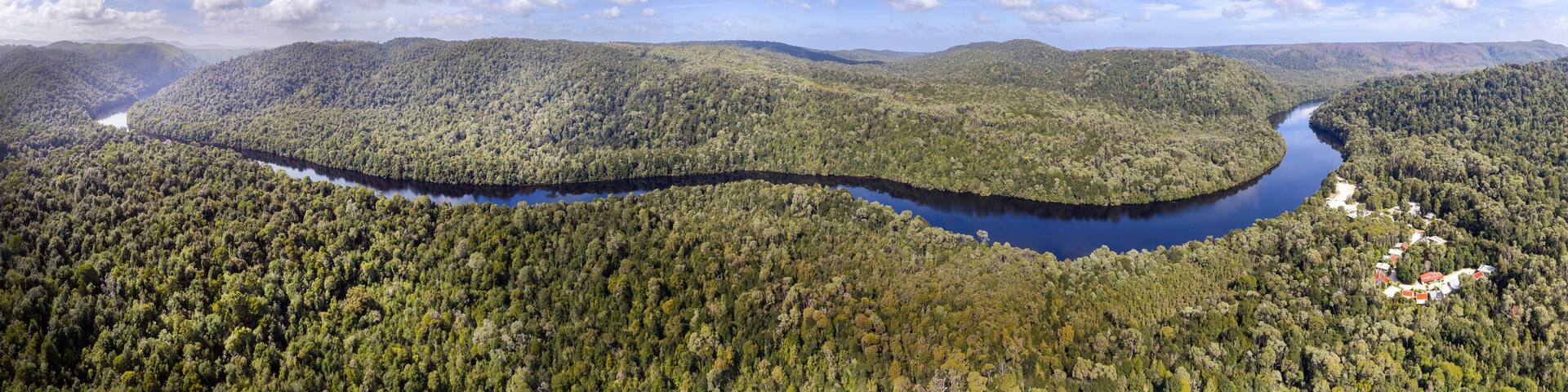 A river winding through a densely forested valley with hills in the background.