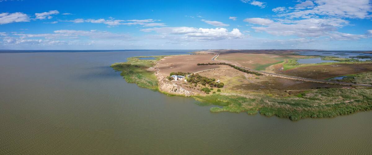 An aerial view of a coastal landscape with a small island, a road, and a body of water.