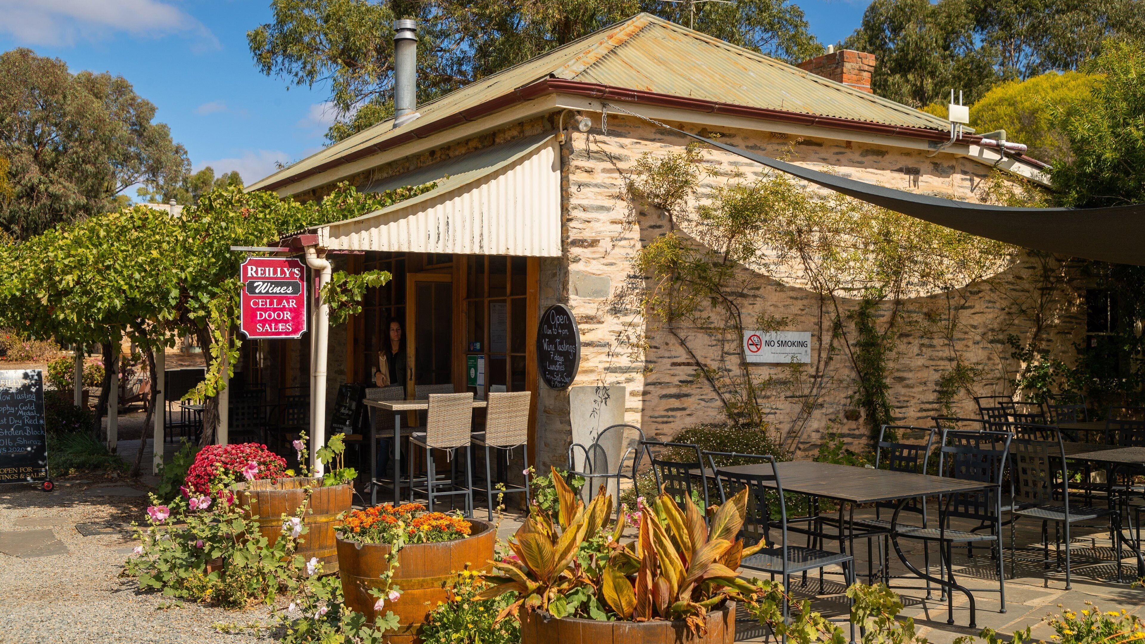 A rustic stone building with a sign for 'Reilly's Wines Cellar Door Sales'.