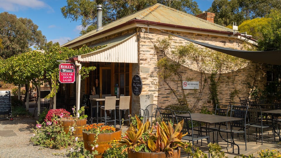 A rustic stone building with a sign for 'Reilly's Wines Cellar Door Sales'.