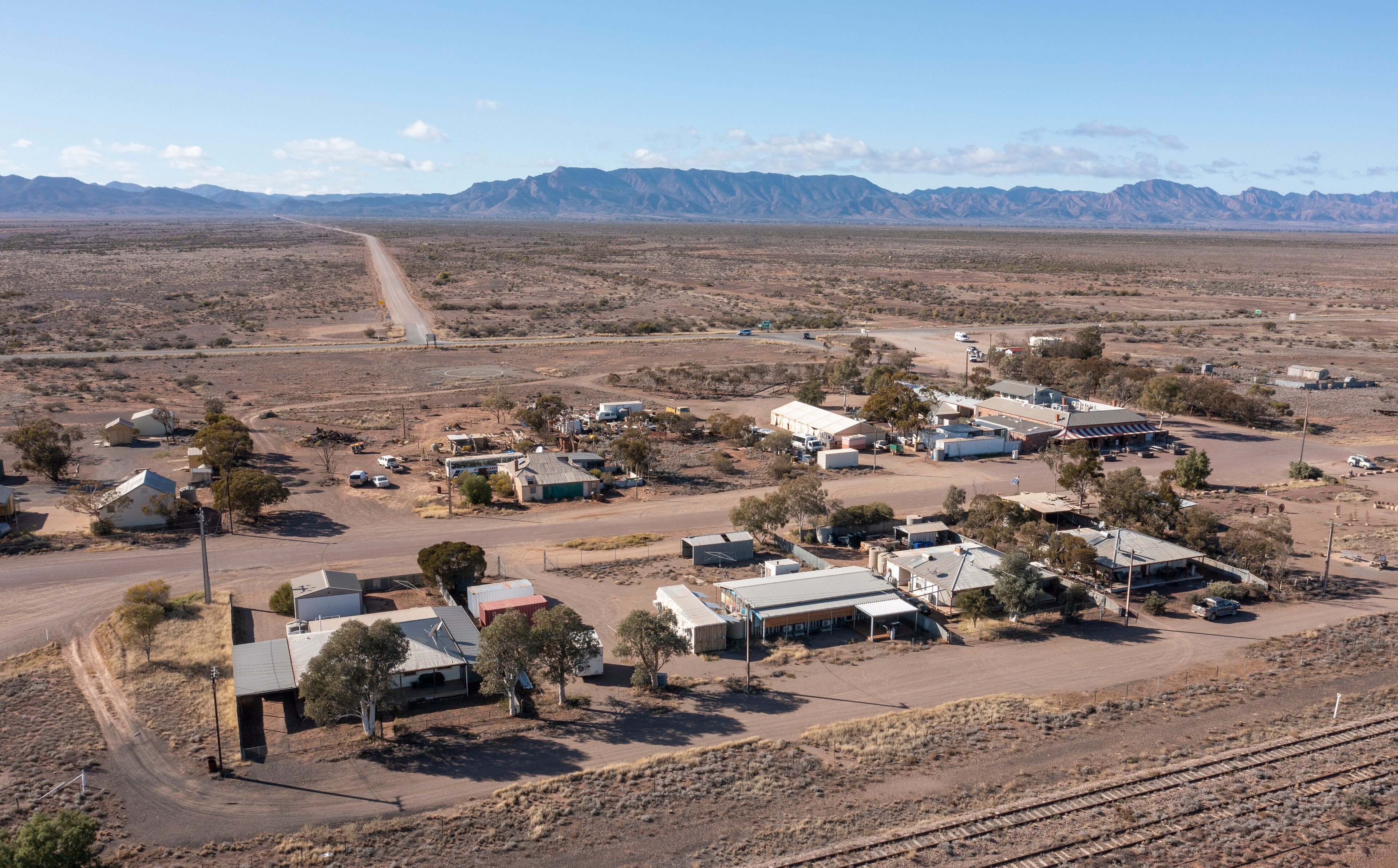 A small town with houses, a road, and mountains in the background.