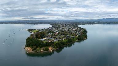 Aerial view of a peninsula with houses and boats in a bay in Omokoroa, Bay Of Plenty, New Zealand. The image shows the beauty of the landscape and the lifestyle of the people who live there.
