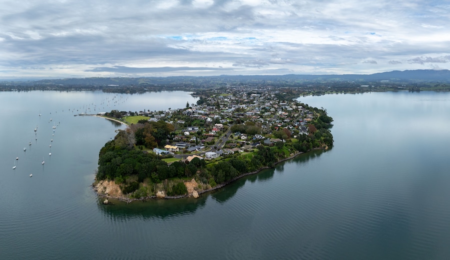 Aerial view of a peninsula with houses and boats in a bay in Omokoroa, Bay Of Plenty, New Zealand. The image shows the beauty of the landscape and the lifestyle of the people who live there.
