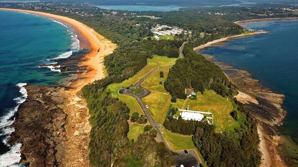 A coastal landscape with a beach, a golf course, and a residential area.