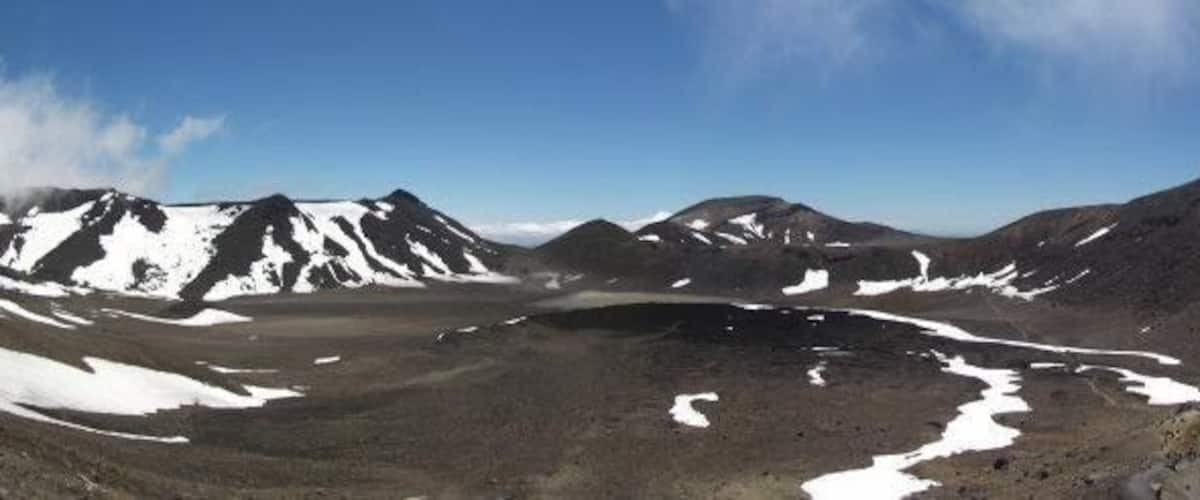 A mountainous landscape with snow patches, a turquoise lake, and a clear sky.