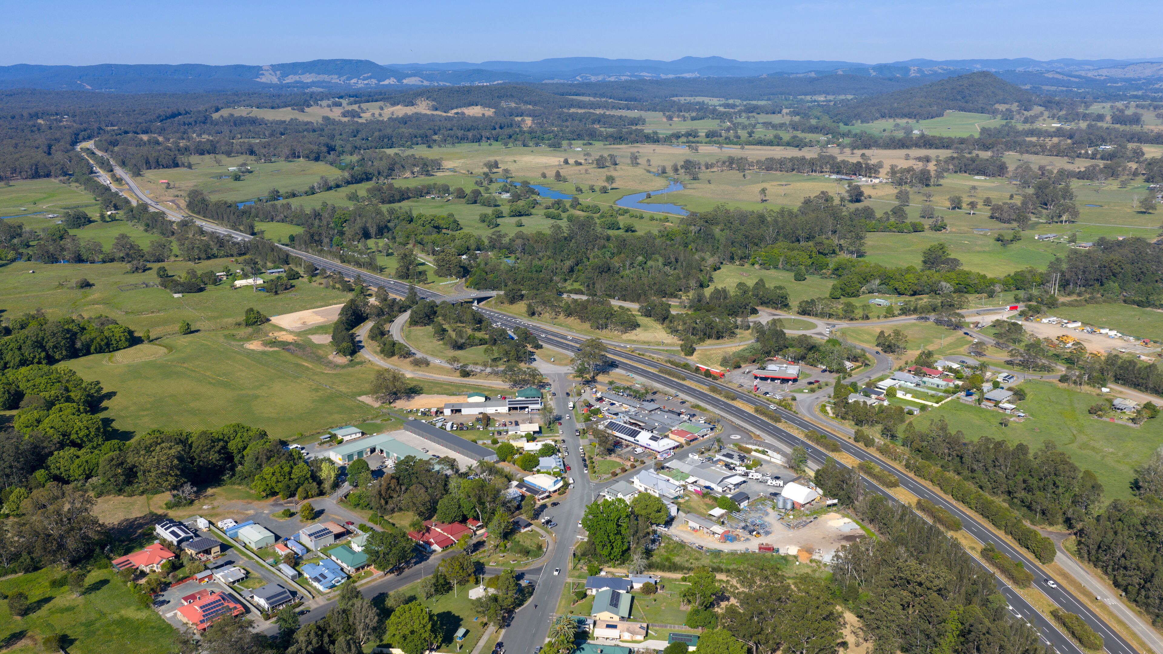 An aerial view of a town with a highway, green fields, and scattered buildings.