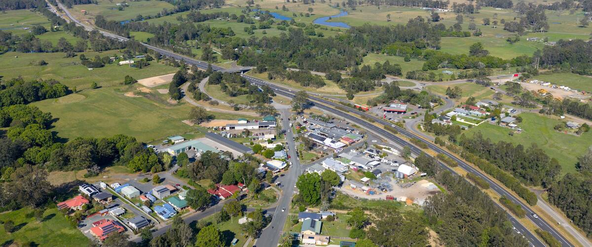An aerial view of a town with a highway, green fields, and scattered buildings.