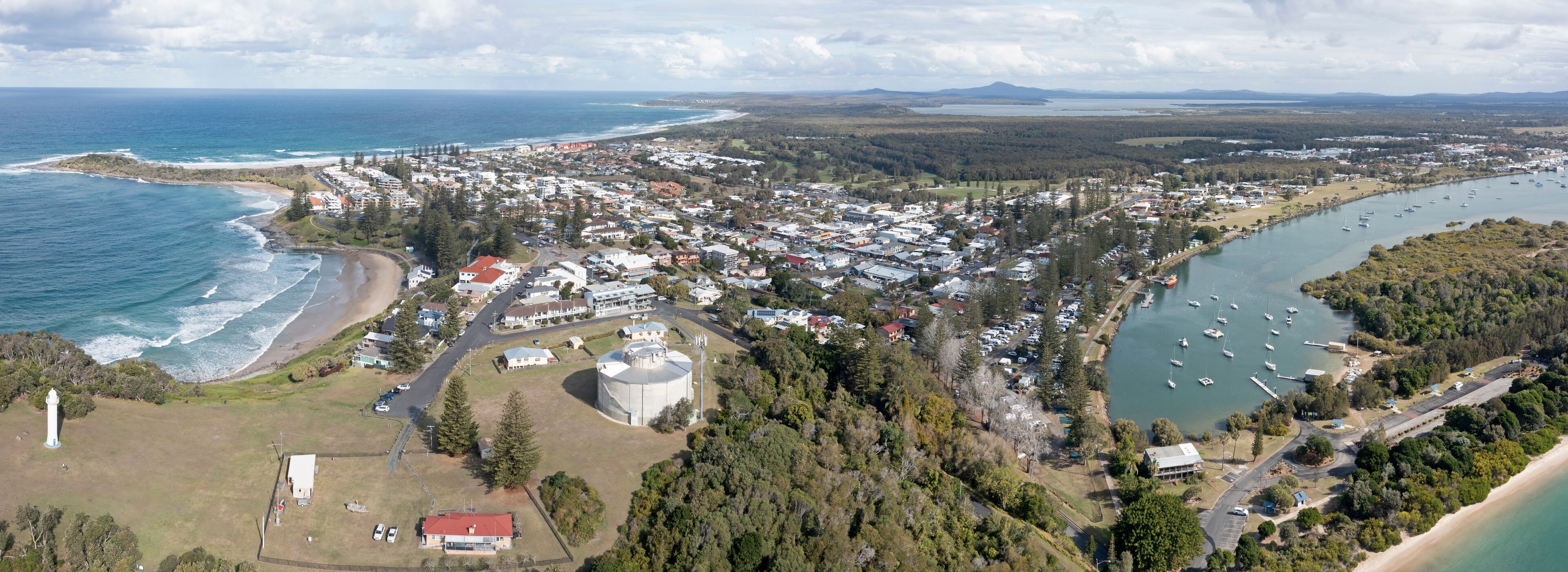 A coastal town with a beach, marina, and dense residential area.