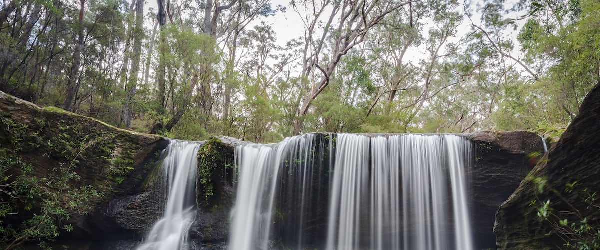 A waterfall cascading over rocks in a forested area.