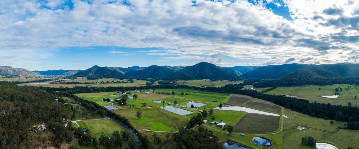 A mountainous landscape with a valley, fields, and scattered buildings.