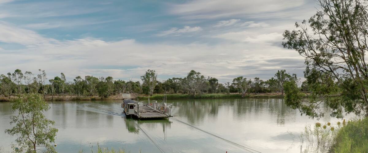 A calm lake with a small boat docked on the shore, surrounded by trees and vegetation.
