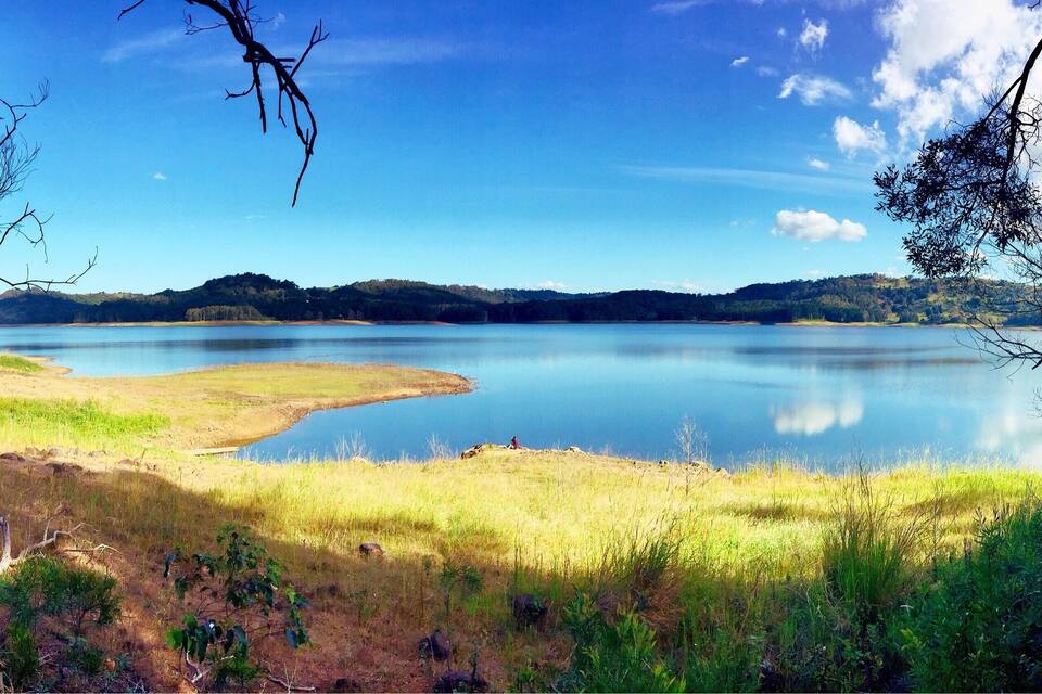 A calm lake surrounded by grassy fields and hills.